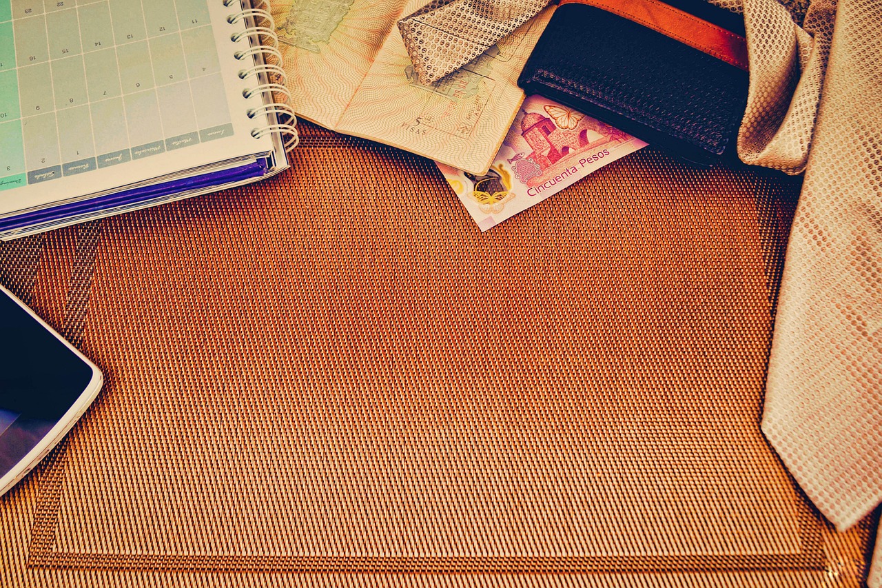 Open passport with travel stamps, a necktie and a wallet laid out beside a planner on a consultant's desk